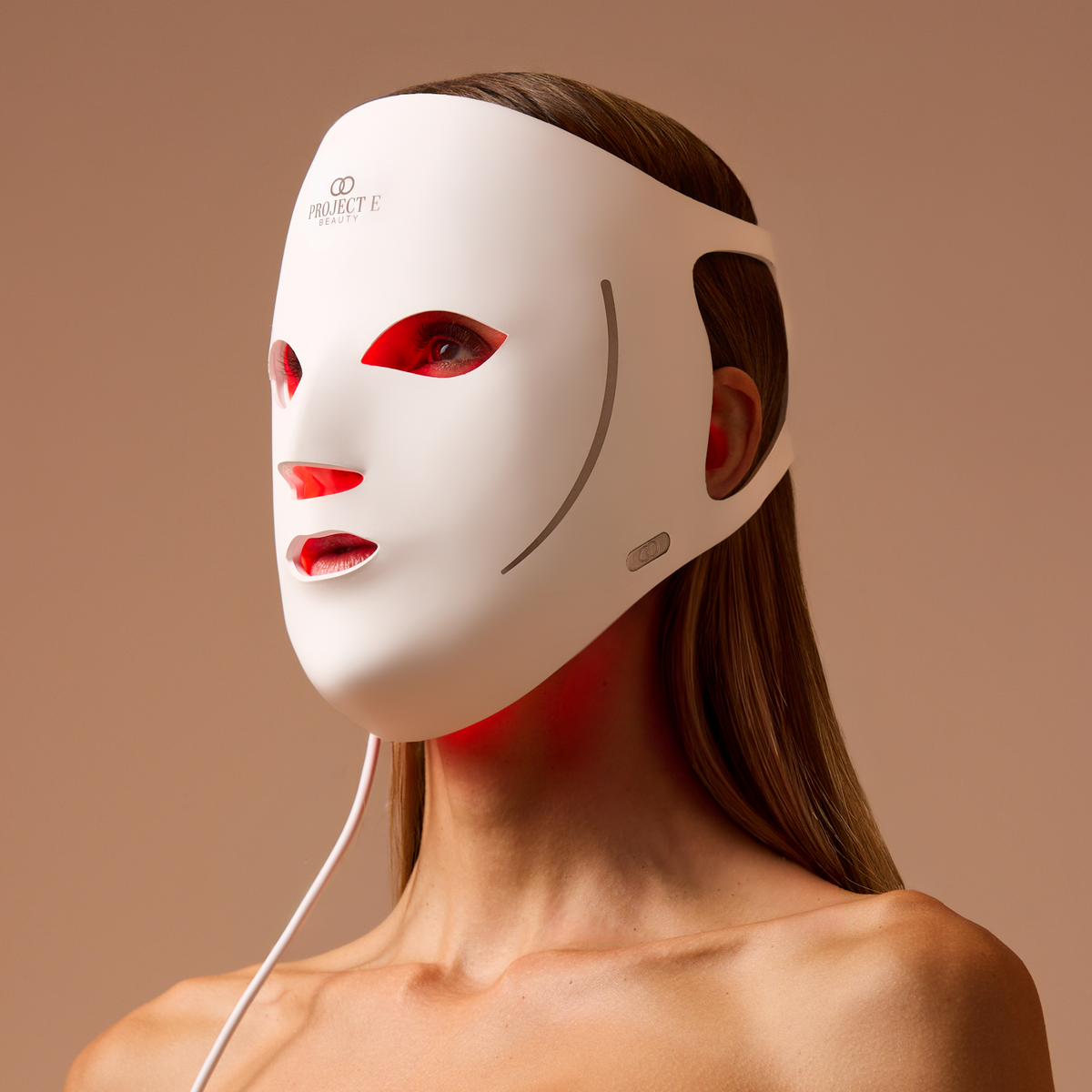 白い LumaLux Face V2 マスクを着用した女性。内側に赤い光が見える